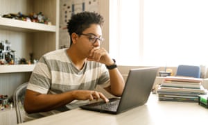 Teenage boy studying with laptop at home.