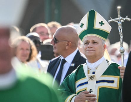 Pope Leo XIV in Lourdes holding a silver staff, flanked by security.