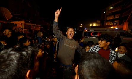 A man raises his hand as Palestinians in Khan Younis wait for news of a ceasefire deal between Hamas and Israel.