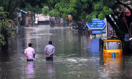 People walk along flooded roads in southern India