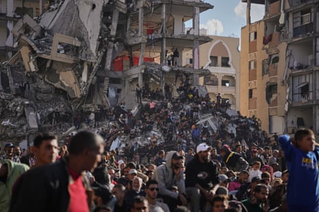 People stand on top of rubble as they watch and celebrate a mass wedding ceremony in Khan Younis, Gaza Strip, 2 December
