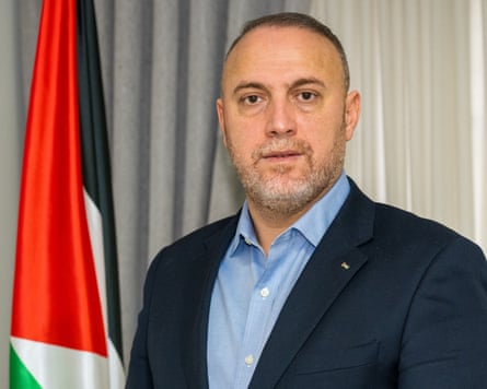 Husam Zumlot next to Palestinian flag