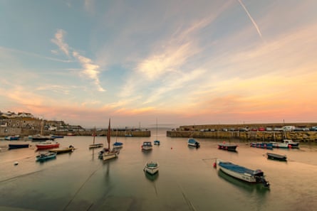Sunset view of Mousehole in Cornwall with boats moored in harbour