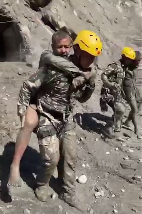 A rescuer carries a survivor to safety.