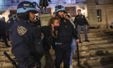 Woman detained by two police officers with helmets and batons