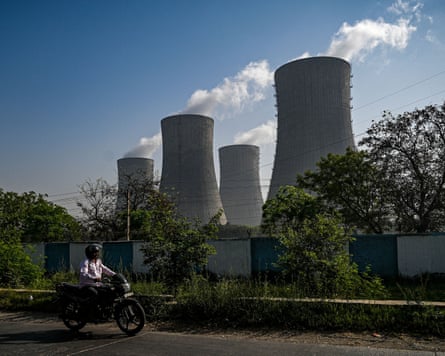 A man rides a motorcycle along a road past the National Thermal Power Corporation plant in Dadri.