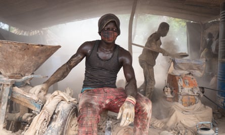 Two teenagers work equipment in hazardous, dusty conditions