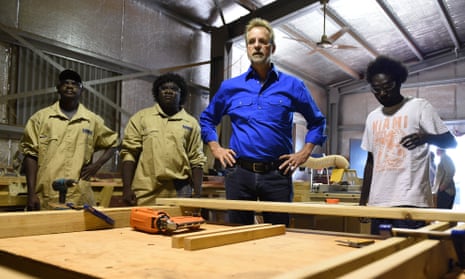 white man stands next to young Indigenous men in a workshop
