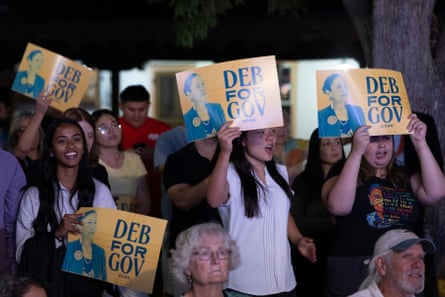 Supporters of Deb Haaland cheer and hold up orange “Deb for Gov” signs at an evening rally