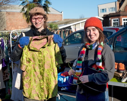 Two women at a car boot sale, one holding a colourful shirt