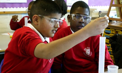 Pupils wearing safety glasses conduct an experiment