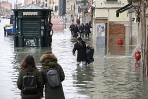 People wade through water during the high tide