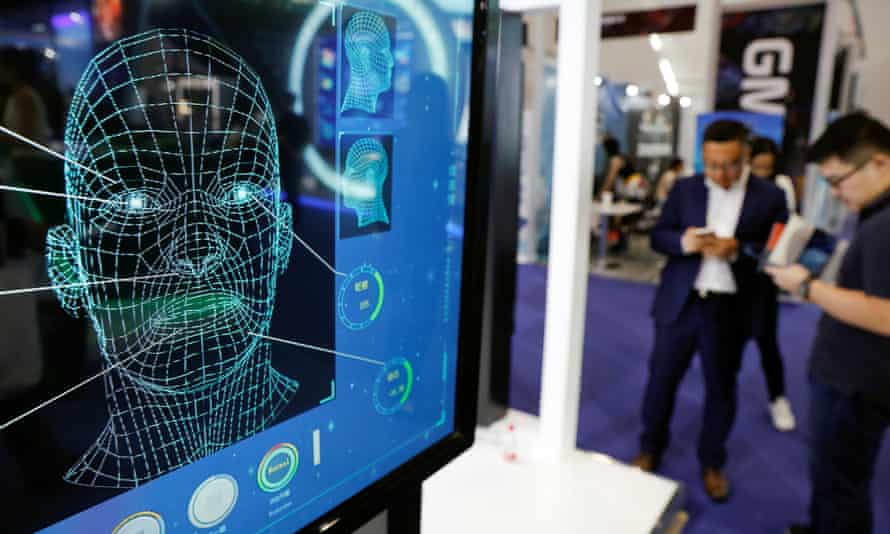Visitors check their phones behind the screen advertising facial recognition software during Global Mobile Internet Conference (GMIC) .