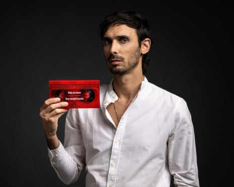 Director Robert dos Santos i a white shirt, holds the VHS of his film This Is How the World Ends