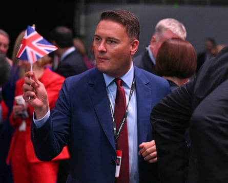 Wes Streeting holding a small union flag with people in background