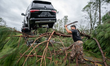 A truck driver uses a machete to clear fallen trees and branches.