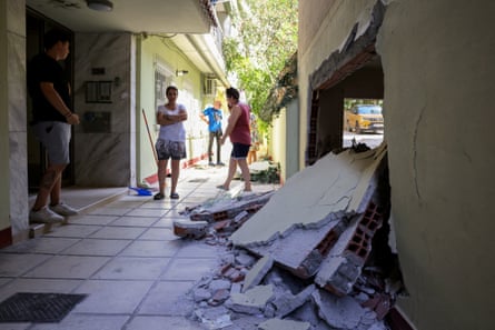 A large hole in a wall in a building, people stood nearby staring at it