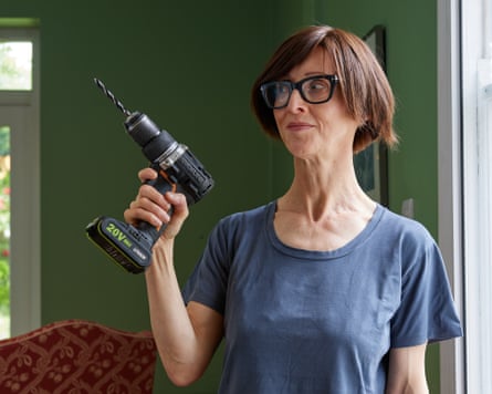Emma Beddington, in a blue T-shirt, glances at a drill she is holding.