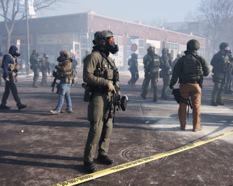 Masked ICE agents stand amid teargas in Minneapolis.