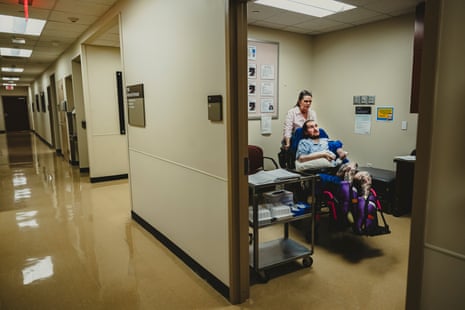 A wide view of a woman and her son in a wheelchair in a doctor’s office