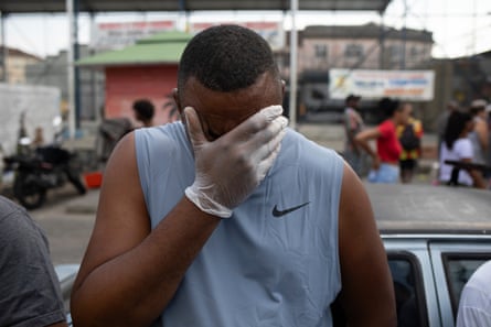 A man covers his face with a gloved hand.