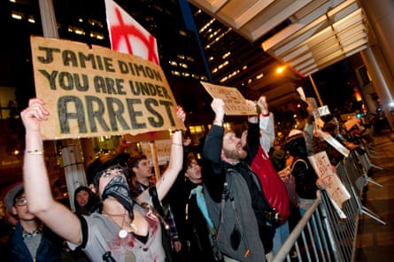 a person holds a sign that reads ‘Jamie Dimon you are under arrest’