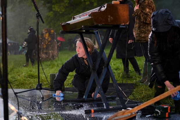 Emily Eavis helps to dry the stage after rainfall at the Stone Circle, before Haim start their performance.
