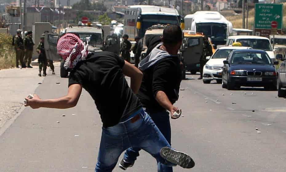Palestinian demonstrators throw stones towards Israeli forces during clashes at the Hawara checkpoint, south of the West Bank city of Nablus.