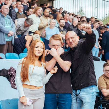 West Ham fans pitch side with the man in the centre making a Hammers sign