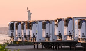 The Statue of Liberty is seen behind refrigeration trucks that function as temporary morgues at the South Brooklyn Marine Terminal during the coronavirus pandemic on May 25, 2020 in New York City.