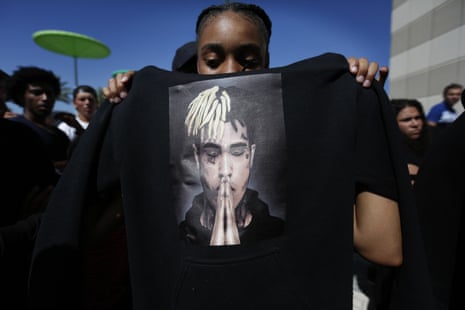 Anneyah Lawson holds up a sweatshirt with an image of the late rapper XXXTentacion, before his memorial in Florida.