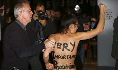A Femen activist is led away by security staff member inside the film institute La Cinematheque Francaise in Paris