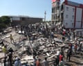 A crowd of people milling over large pile of rubble