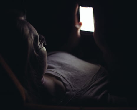A young woman using a mobile phone in dark room