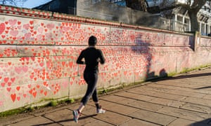 A  jogger runs past the UK’s national Covid memorial wall along the Thames in London.