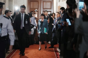 Sanae Takaichi walks down a corridor surrounded by photographers
