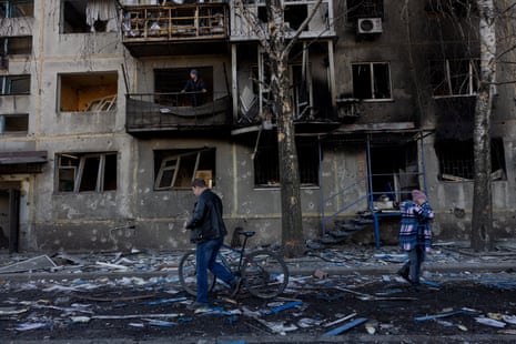 People walk by a damaged residential building after a strike in Dobropillia, Donetsk region, on Saturday.