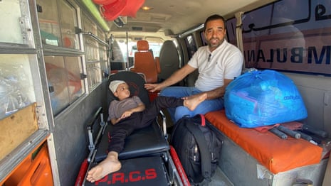 Ameer Joma, a Palestinian boy who was injured in an Israeli strike, waits with his father in an ambulance at the Rafah border crossing for treatment in an Egyptian hospital