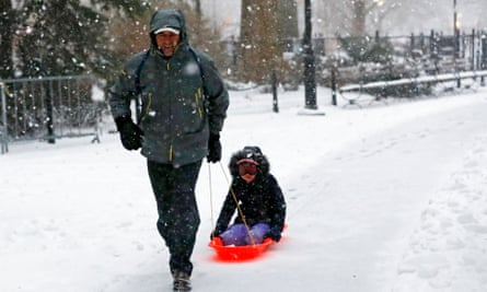 A man pulls his child through a snowy Washington Square Park in New York City.