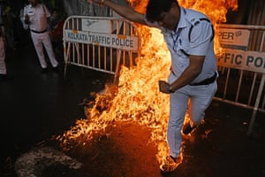 A police officer tries to douse flames from an effigy