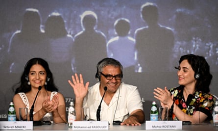 Setareh Maleki, in a sleeveless top and with long hair, sits next to Mohammad Rasoulo, in a short-sleeved shirt, glasses and a headset, and on his right Mahsa Rostami, smiling and applauding, all of them with microphones in front of them and the silhouette of five people on a screen behind them