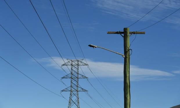 A high voltage transmission line and a electricity power pole against a blue sky with a few white clouds