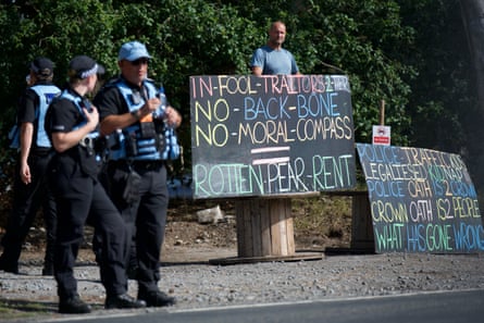 A man stands behind two large blackboard-style placards emblazoned with political slogans