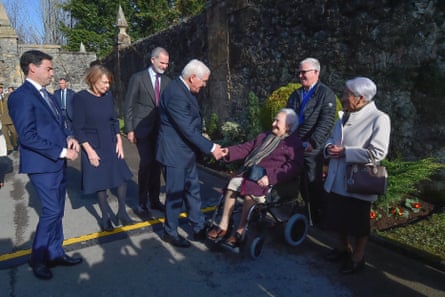 Steinmeier shakes hands with woman in wheelchair next to another woman with several other people around