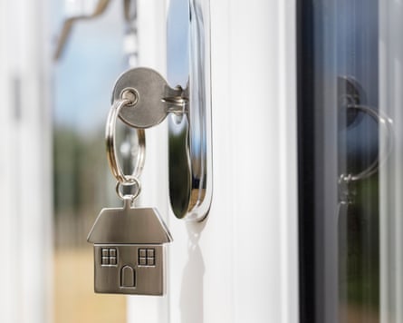 House key on a house-shaped silver keyring in the lock of a door