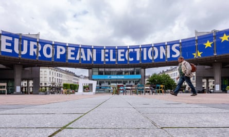 People walk outside the European parliament which is advertising the European elections on a banner.