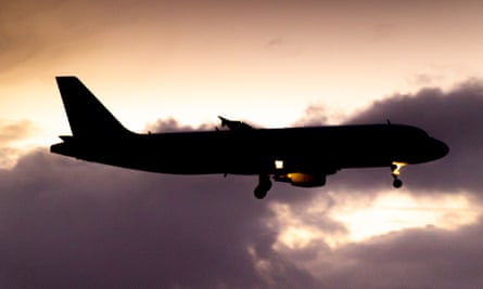 Silhouette of a landing aircraft with a cloudy background after the sunset.