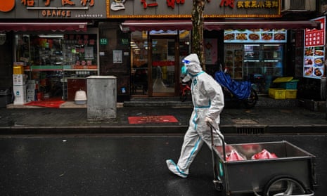 A worker wearing protective equipment walks near a locked down neighbourhood after the detection of new cases of Covid-19 in the Huangpu district of Shanghai on 17 March 2022.