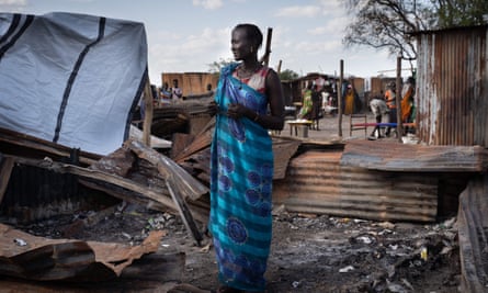 A woman stands at her burnt tea shop in a market in Gumuruk, South Sudan