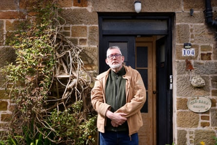 Neil Heydon-Dumbleton stands in front of an old stone house.